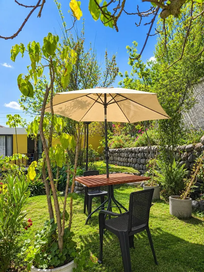Mesa bajo sombrilla entre la vegetación del jardín
